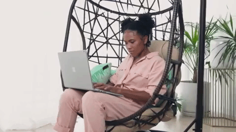 Woman sat in a swinging chair working on an Apple Macbook